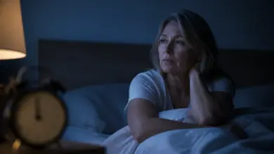 Frau liegt nachts wach im Bett bei gedämpftem Licht
