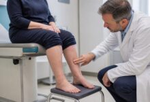 Arzt untersucht die leicht geschwollenen Knöchel einer Patientin